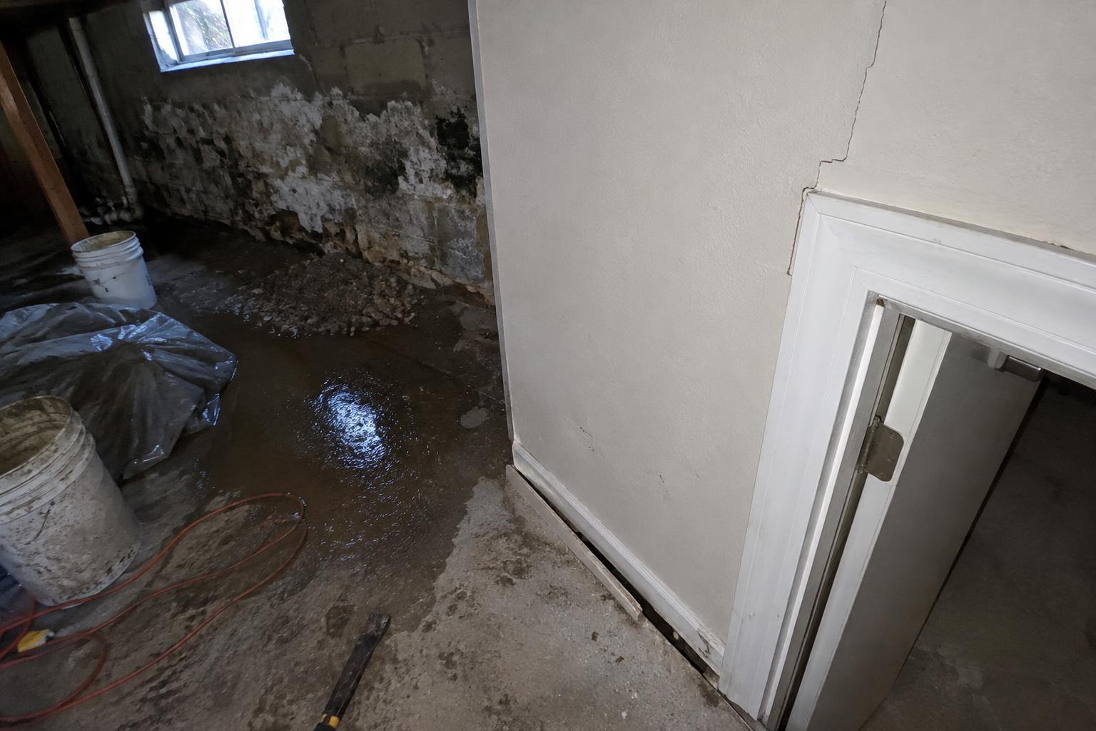 A hairline stair-step crack running through the corner of an interior drywall wall above a door frame in a Rolling Hills home, with the baseboard slightly separated from the floor below it.